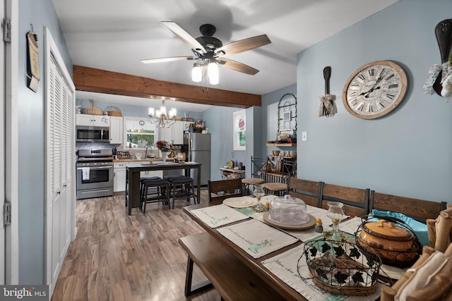 dining room featuring light wood-type flooring, beam ceiling, and ceiling fan with notable chandelier