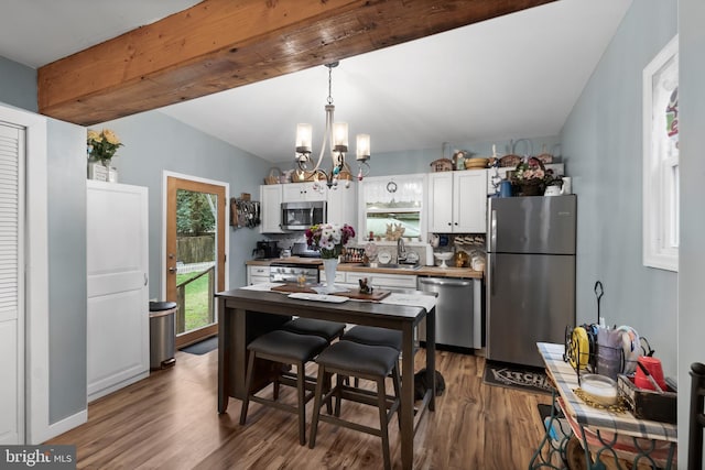 dining space featuring wood finished floors, a notable chandelier, and vaulted ceiling with beams