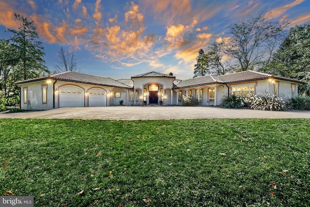 mediterranean / spanish home with a lawn and a garage