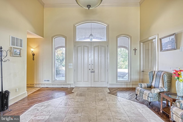 entrance foyer with ornamental molding, light hardwood / wood-style flooring, and a towering ceiling