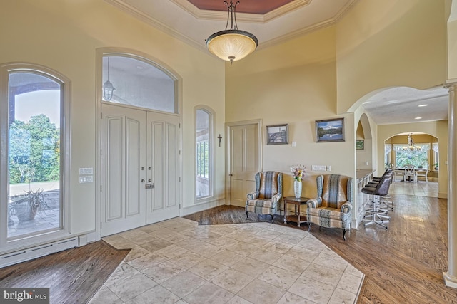 foyer with crown molding, light hardwood / wood-style flooring, and a towering ceiling