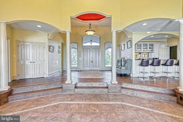 entryway featuring ornate columns, crown molding, and a high ceiling