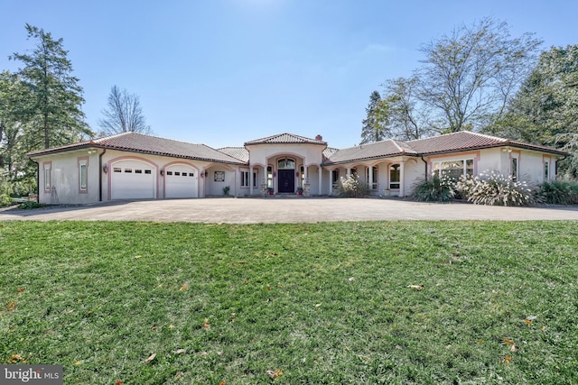 mediterranean / spanish home featuring a front lawn and a garage