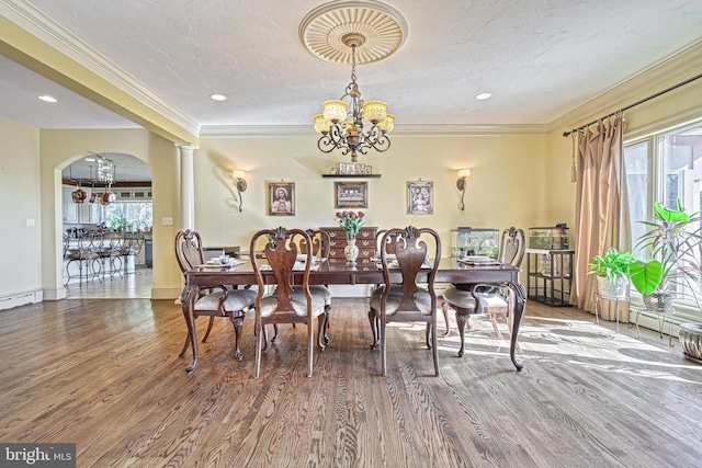 dining space featuring an inviting chandelier, a textured ceiling, wood-type flooring, and crown molding