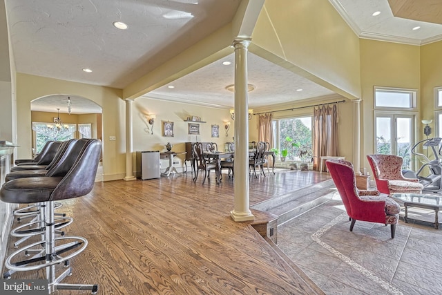 living room with crown molding, ornate columns, hardwood / wood-style flooring, and a textured ceiling