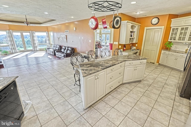 kitchen featuring dark stone countertops, a textured ceiling, hanging light fixtures, and a kitchen bar