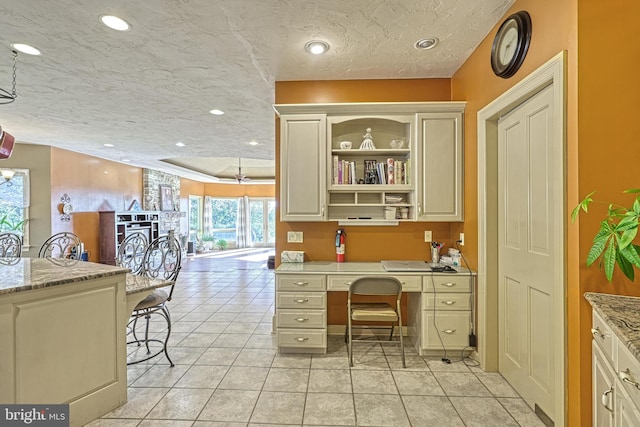 tiled home office with built in desk, a textured ceiling, and a healthy amount of sunlight