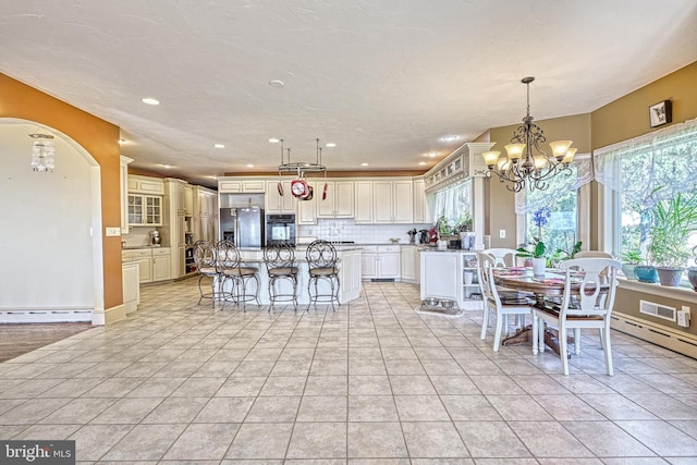 dining space with light tile patterned floors, a textured ceiling, a baseboard radiator, and an inviting chandelier