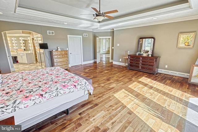 bedroom with ornamental molding, hardwood / wood-style flooring, a tray ceiling, and ceiling fan