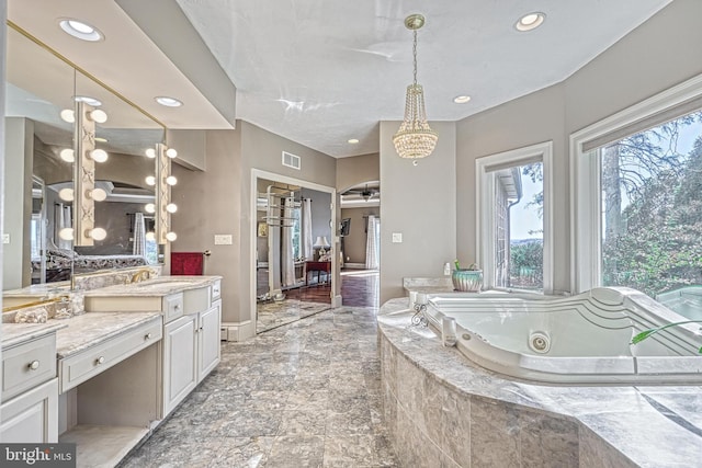 bathroom featuring vanity, a relaxing tiled tub, and ceiling fan