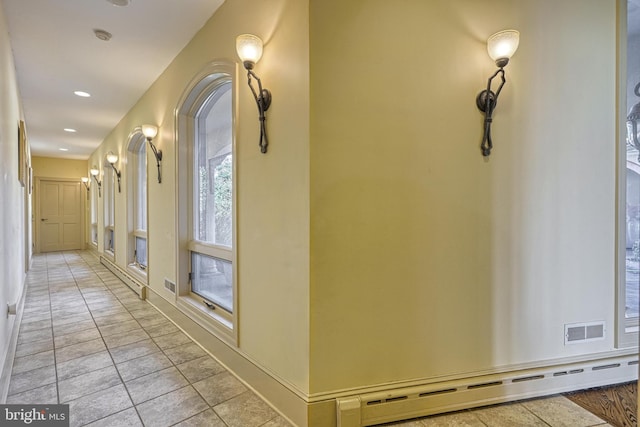 hall with light tile patterned flooring and baseboard heating