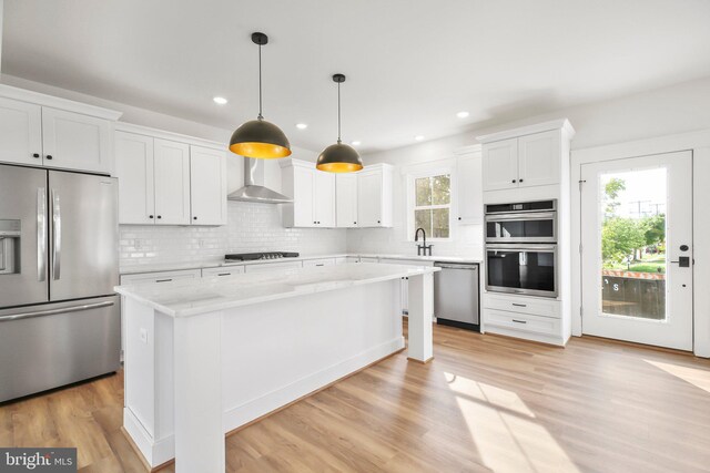 kitchen with a center island, appliances with stainless steel finishes, white cabinets, and plenty of natural light