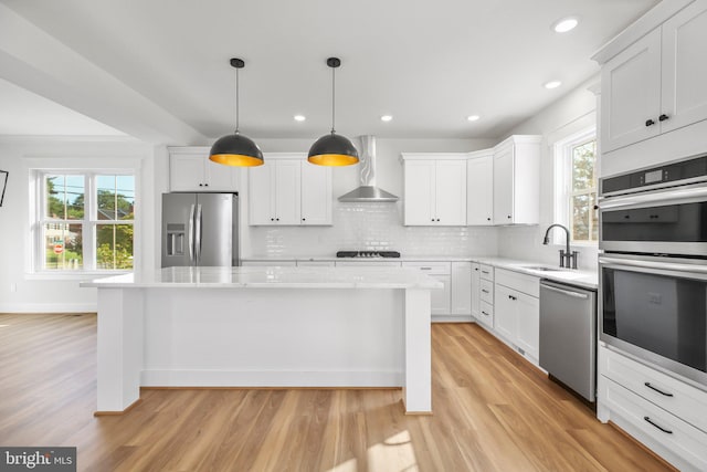 kitchen with white cabinetry, wall chimney range hood, stainless steel appliances, and light hardwood / wood-style floors