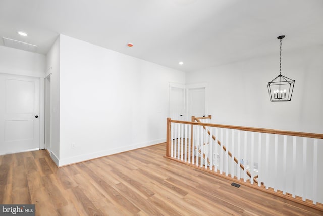 spare room featuring light hardwood / wood-style floors and a chandelier