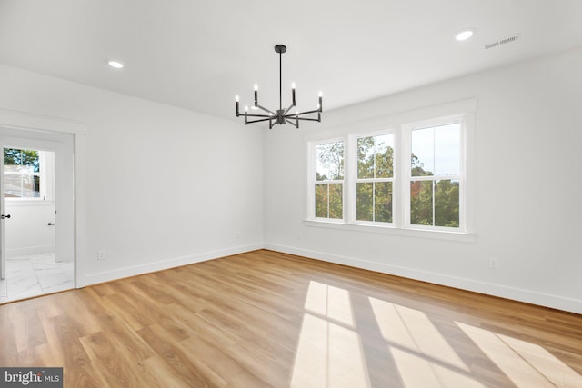 unfurnished dining area with light hardwood / wood-style floors and an inviting chandelier