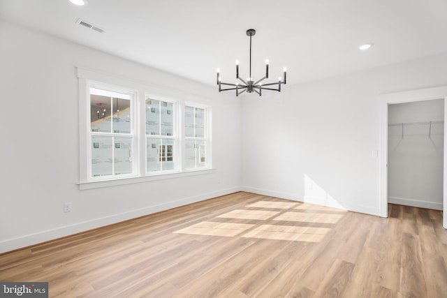 unfurnished dining area with an inviting chandelier and light wood-type flooring