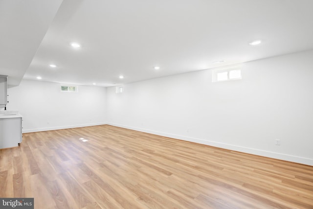 basement with light hardwood / wood-style floors and a healthy amount of sunlight