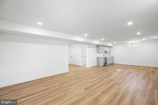 basement with light hardwood / wood-style floors and sink