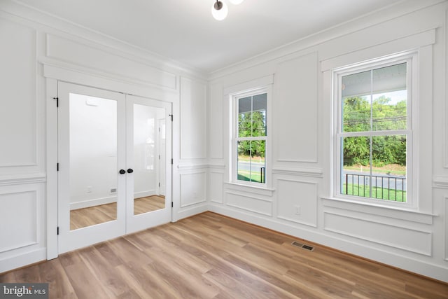 unfurnished room with french doors, crown molding, and light wood-type flooring