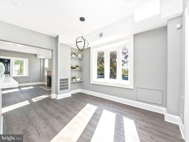 unfurnished living room with dark hardwood / wood-style floors and built in shelves