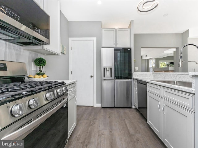 kitchen featuring sink, stainless steel appliances, white cabinets, light stone counters, and light hardwood / wood-style flooring