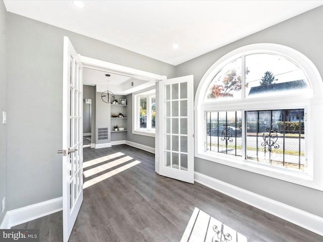 interior space with french doors, a healthy amount of sunlight, dark wood-type flooring, and built in shelves