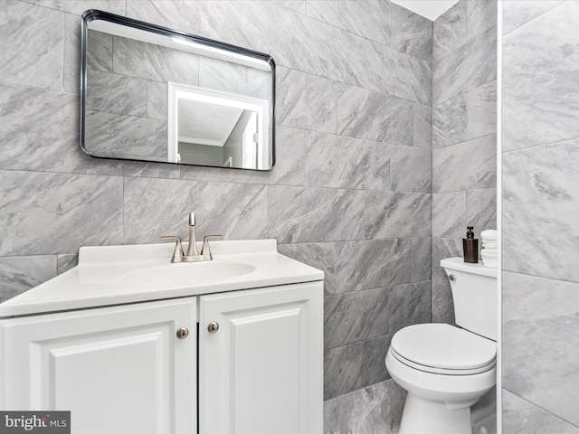 bathroom with vanity, toilet, and tile walls