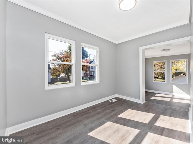 unfurnished room with ornamental molding, dark wood-type flooring, and a healthy amount of sunlight