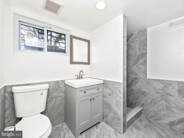 bathroom with toilet, vanity, a shower, and tile walls