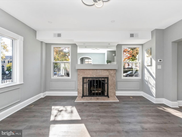 unfurnished living room with dark wood-type flooring, plenty of natural light, and a tile fireplace