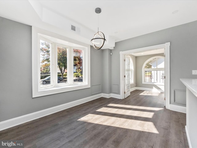 unfurnished dining area with dark wood-type flooring and a chandelier