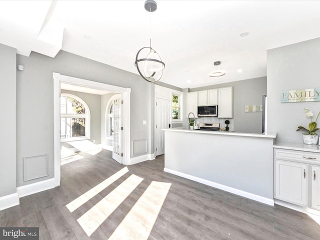 kitchen with white cabinetry, stainless steel appliances, decorative light fixtures, and dark hardwood / wood-style floors