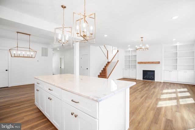 kitchen featuring light hardwood / wood-style flooring, white cabinets, a fireplace, and pendant lighting