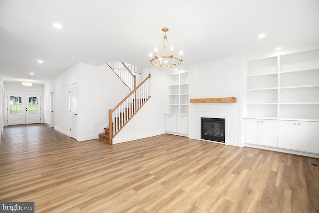 unfurnished living room featuring a chandelier, light hardwood / wood-style flooring, a fireplace, and built in features