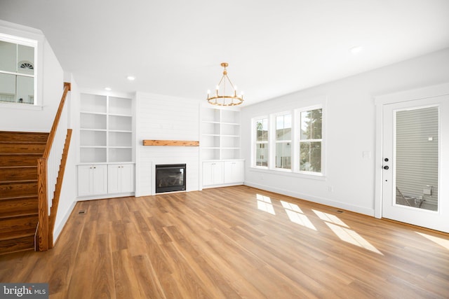 unfurnished living room with an inviting chandelier, hardwood / wood-style flooring, and a fireplace