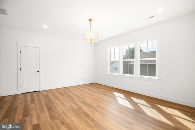 spare room featuring a notable chandelier and wood-type flooring