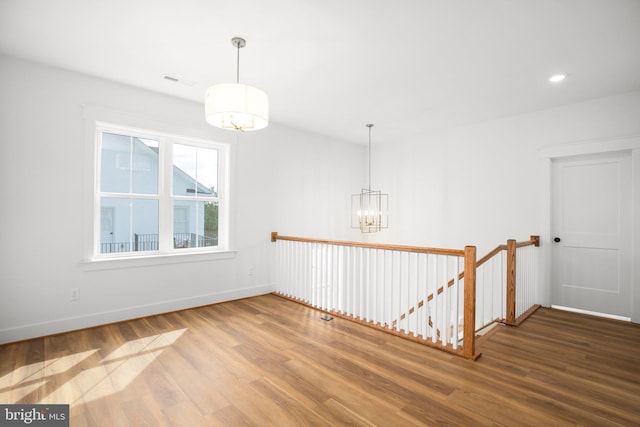 spare room featuring hardwood / wood-style flooring and a chandelier