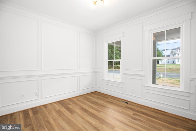 unfurnished room with a wealth of natural light, ornamental molding, and wood-type flooring