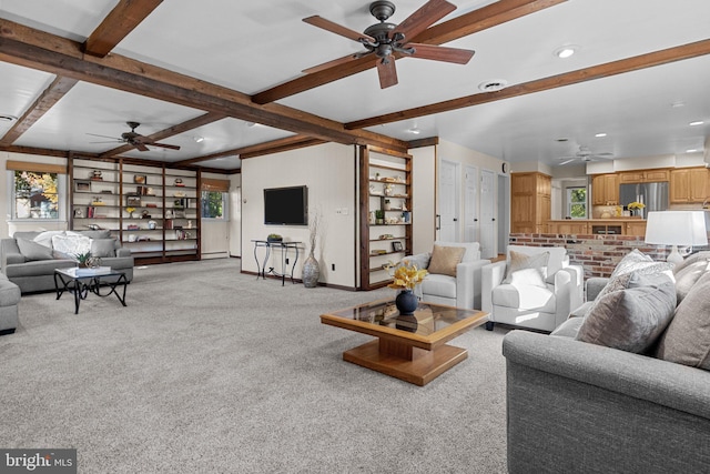 living room with beam ceiling, light carpet, and ceiling fan