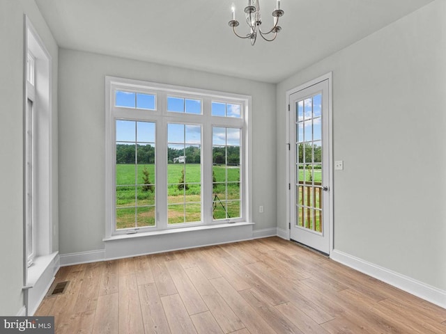 doorway to outside with a chandelier and light hardwood / wood-style flooring