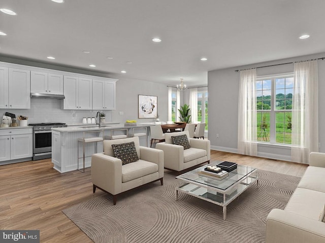 living room featuring sink, light hardwood / wood-style floors, and a chandelier