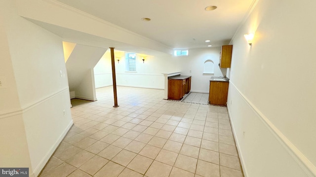 basement with crown molding and light tile patterned floors