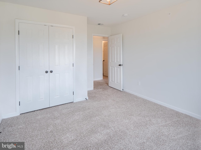 unfurnished bedroom featuring a closet and light colored carpet