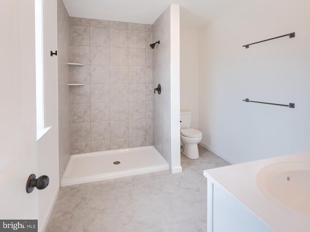 bathroom featuring vanity, toilet, tile patterned floors, and a tile shower