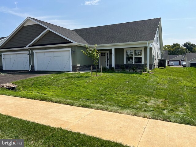 view of front of house featuring a front yard, a garage, and cooling unit