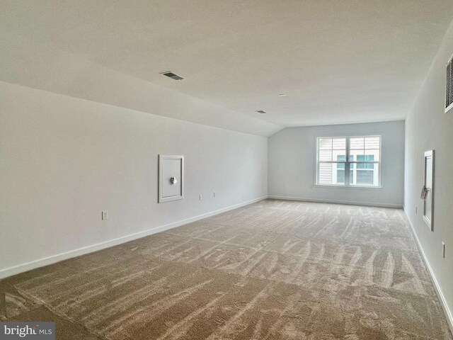 empty room featuring lofted ceiling, carpet, and a textured ceiling