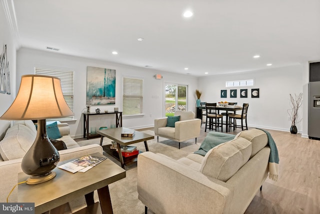 living room with crown molding and light hardwood / wood-style flooring