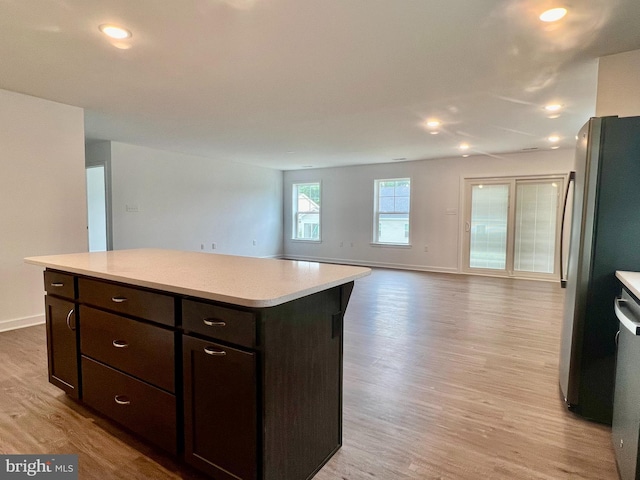 kitchen featuring stainless steel fridge, a center island, dark brown cabinets, and light hardwood / wood-style floors