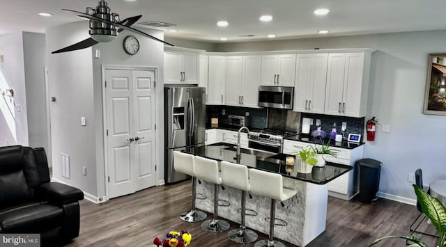 kitchen with a center island with sink, appliances with stainless steel finishes, white cabinets, and tasteful backsplash