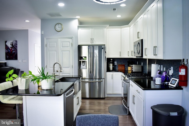 kitchen with a kitchen breakfast bar, stainless steel appliances, sink, white cabinetry, and dark hardwood / wood-style flooring